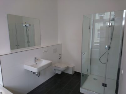 Modernisiertes Badezimmer mit bodengleicher Dusche und sauber ausgeführten Wandflächen in Köln