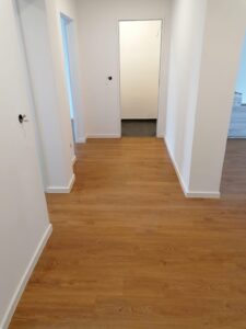 Renovierter heller Flur mit Parkettboden und frisch gestrichenen weißen Wänden in Köln