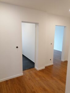 Renovierter Durchgangsbereich mit weißen Wänden, Türöffnungen und Holzfußboden in Köln